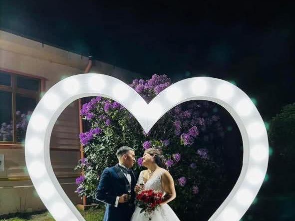 Novios frente a un arco de corazón iluminado
